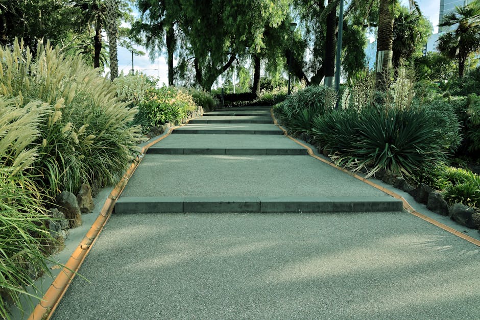 Nowoczesna, minimalistyczna ścieżka betonowa prowadząca przez zadbany ogród