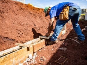 pracownik budowlany sprawdzający poprawność wylewki betonowej na fundamentach domu