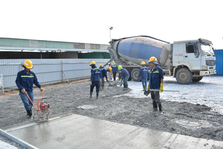 pracownik budowlany wygładzający świeżą wylewkę betonową na budowie domu