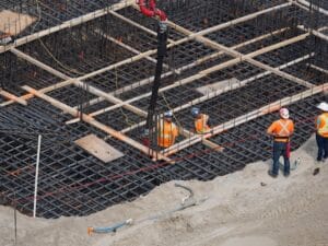 pracownicy budowlani wylewający beton na fundamenty domu